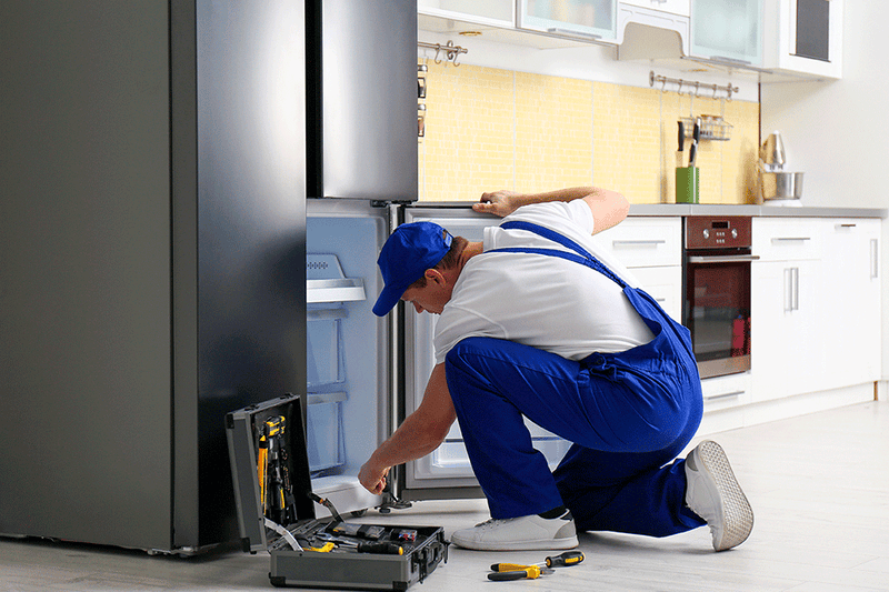 Male technician repairing a refrigerator in Edmonton