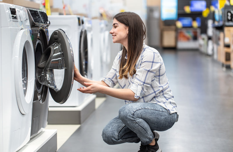 Young woman in store chooses used washing machine