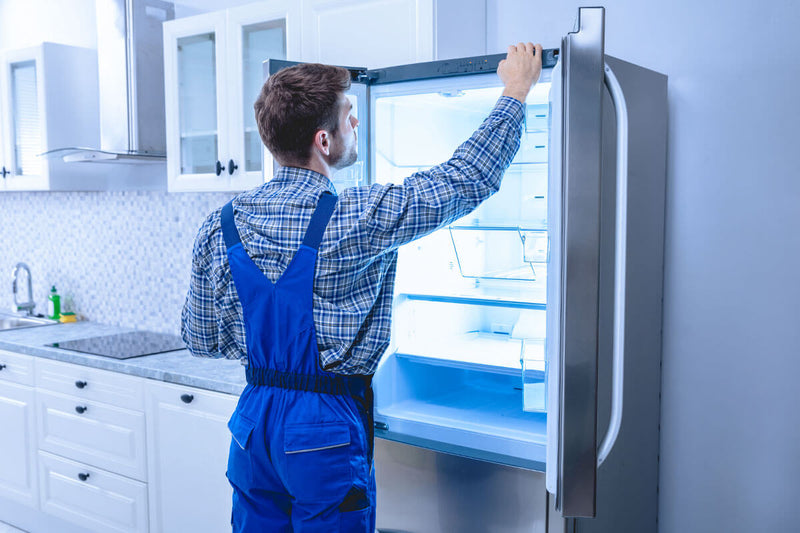 A man is fixing a refrigerator