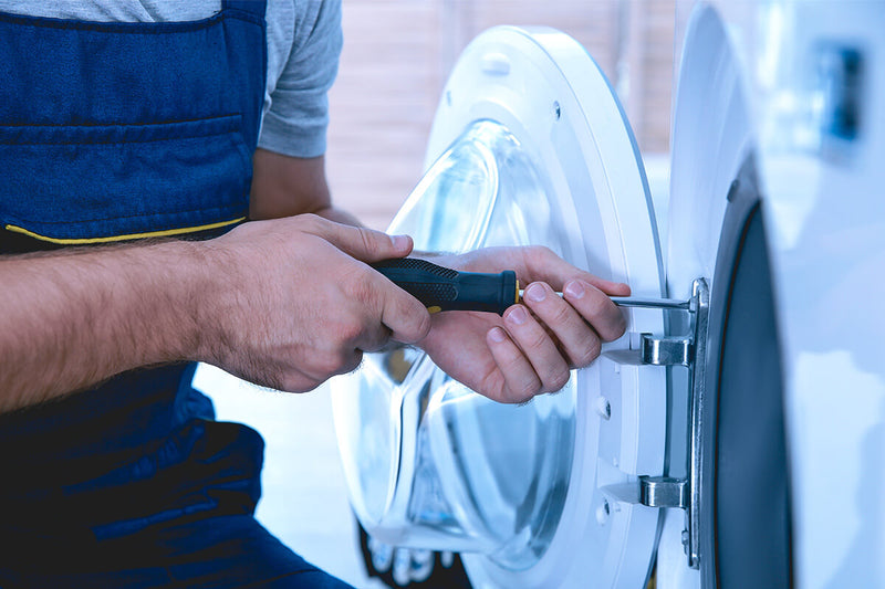 A man performing appliance repair on a washing machine in Edmonton